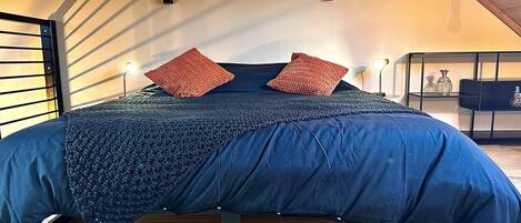 A bedroom with a bed, two wall-mounted lights, and a wooden ceiling.