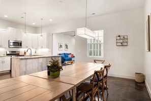 A modern kitchen with white cabinets, a central island, and a dining area with a wooden table and chairs.