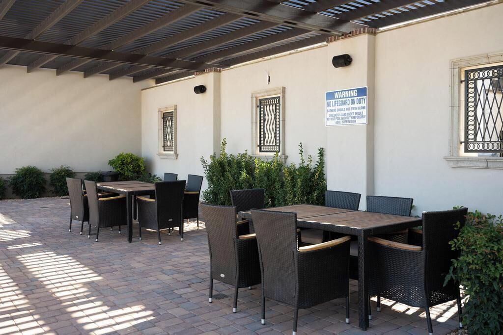 An outdoor patio area with tables and chairs, a warning sign, and a covered ceiling.