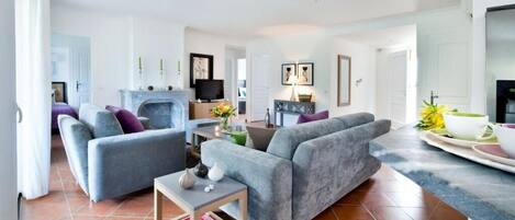 A spacious living room with a fireplace, grey sofas, and a coffee table.