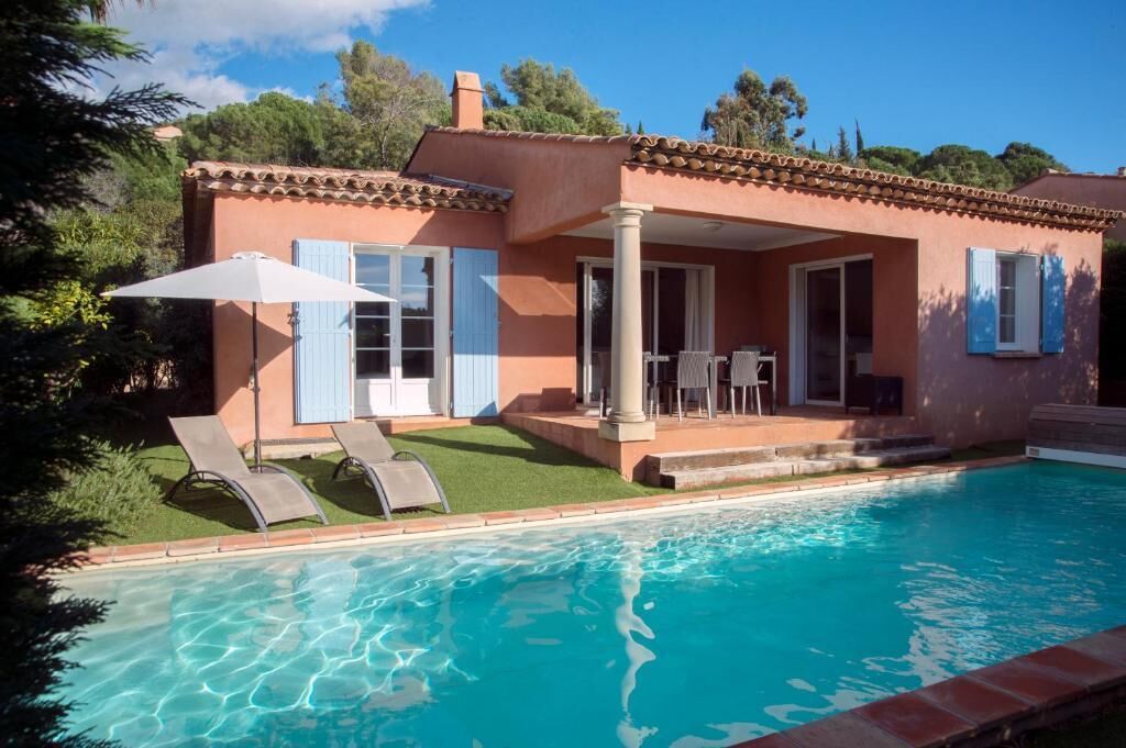 A house with a swimming pool, a patio with chairs, and a covered outdoor area.