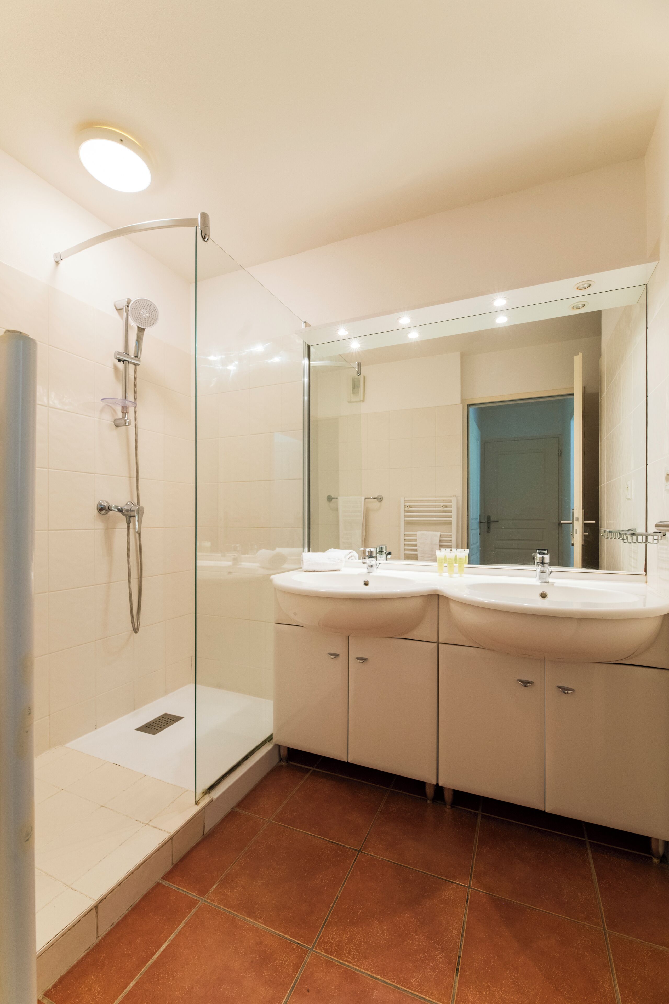 A modern bathroom with a glass-enclosed shower, two sinks, and a large mirror.