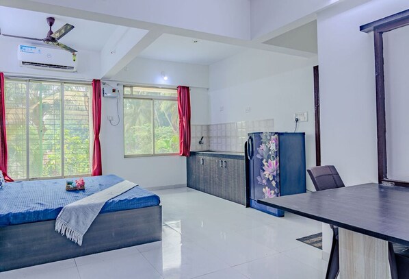 A modern room with a bed, a desk, and a kitchenette.