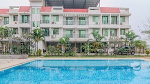 Un hôtel moderne doté d’une piscine, de nombreux balcons et d’une végétation luxuriante.