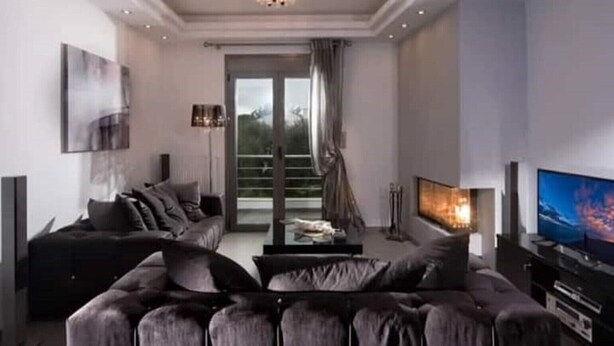 Ein modernes Wohnzimmer mit einer Couch, einem Fernseher und einem Kamin.
