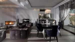 Ein modernes Wohnzimmer mit Kamin, Fernseher und Essbereich mit Stühlen und Tisch.