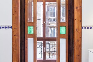 A wooden-framed door with glass panels, a metal gate, and a view of a building with multiple windows and balconies. - Can Boss Turismo de Interior  (Palma de Mallorca)