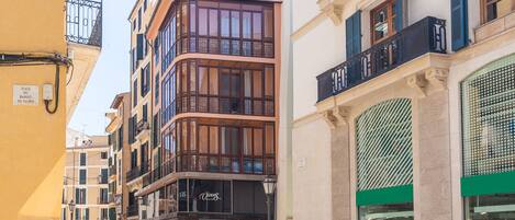 Una calle con edificios de varios pisos, comercios y personas caminando.