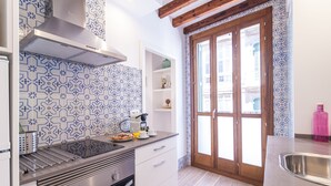 Una cocina moderna con estufa de acero inoxidable, armarios blancos y baldosas azules con diseño.
