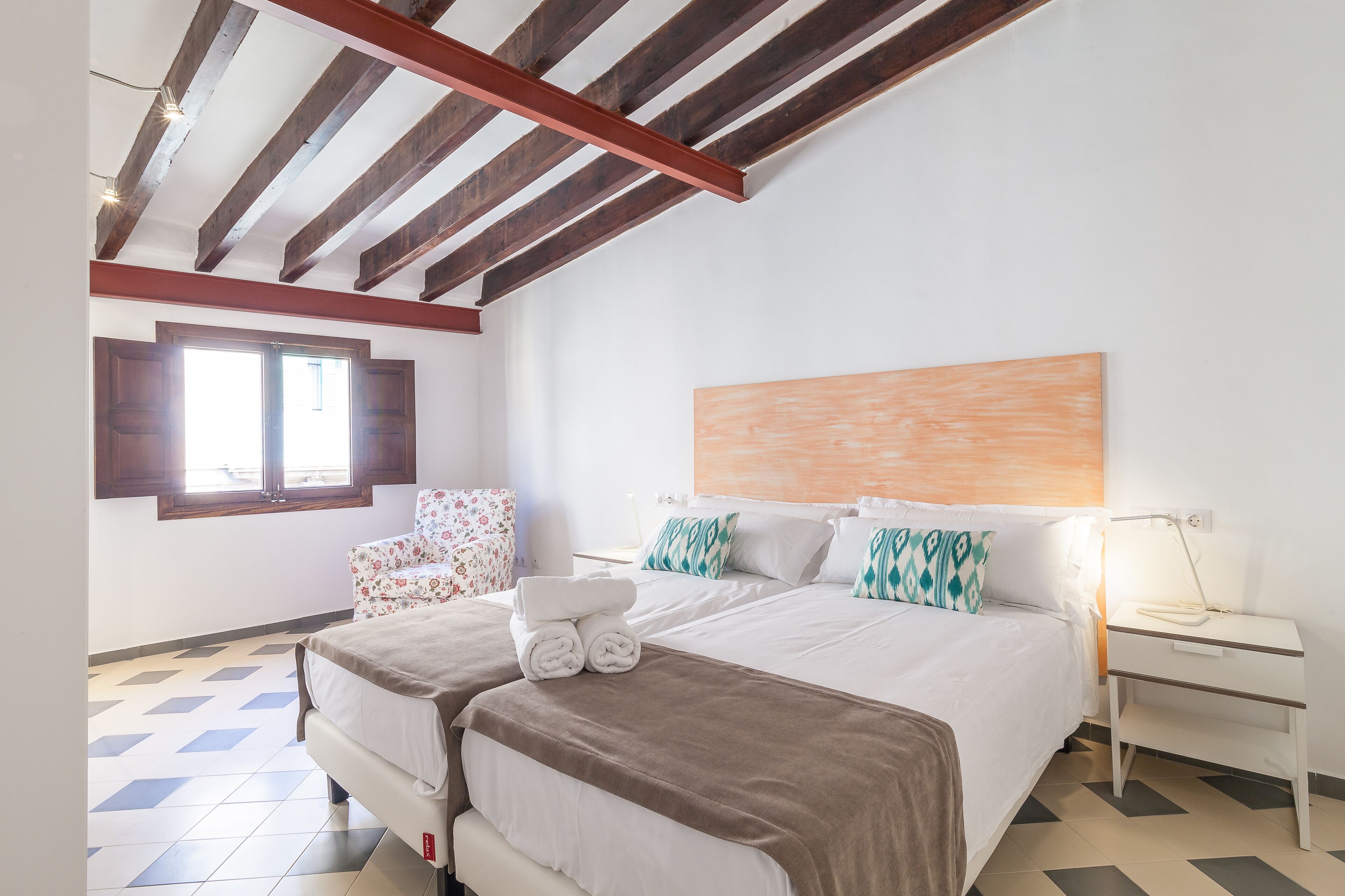 A bedroom with a bed, a nightstand, a chair, and a window.