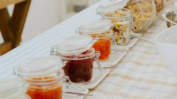 A buffet table with various food items in glass containers, a wooden table, and a checkered tablecloth.