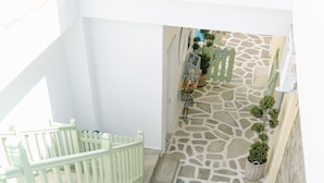 A courtyard with a stone floor, a green railing, and potted plants. - Xenios Zeus Hotel  (Sithonia)