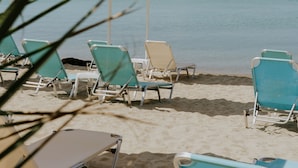 A beach with several sun loungers and umbrellas, a sandy shore, and a clear view of the sea. - Xenios Zeus Hotel  (Sithonia)