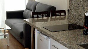 Una cocina compacta con armarios blancos, encimera de granito y estufa integrada.