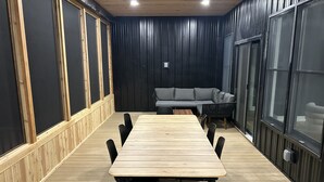 A conference room with a long wooden table, black chairs, a gray sofa, and black-framed windows. - Luxurious Speakeasy Lodge, Hot Tub, Wifi & Hidden Speakeasy! Mins from the Caves (Logan)