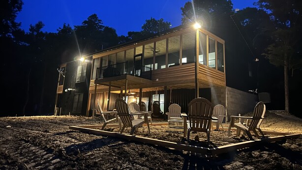 A modern two-story wooden house with a balcony, surrounded by trees. - Luxurious Speakeasy Lodge, Hot Tub, Wifi & Hidden Speakeasy! Mins from the Caves (Logan)