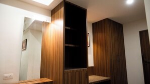 A modern bathroom with wooden cabinetry, a built-in sink, and a mirror. - RAAJ SVASTIK INN (Jamnagar)