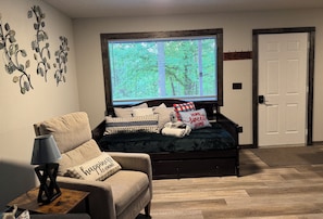 A bedroom with a bed, a TV, a lamp, a chair, and a door.