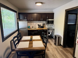 A compact kitchen with dark wooden cabinets, a stainless steel refrigerator, a microwave, and a dishwasher. - Little Owl Cabin #10 - Sleeps 6. Resort Pool&Spa, Fire Pit. SDC 1 mi. Dogs ok! (Branson)