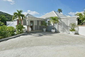 A modern house with a covered driveway, large potted plants, and a white fence. - Ylang Ylang Villa Luxury villa (Flamands)