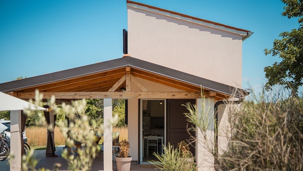 Een modern huis met een overdekte patio, een duidelijke deur en een schoorsteen.