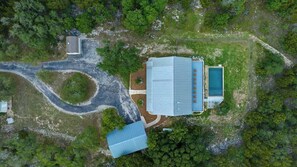 An aerial view of a property with a large building, a swimming pool, and a winding driveway.