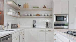 A modern kitchen with white cabinetry, a built-in microwave, and a dishwasher. - The Point-Hill Country Views-Pool+Hot Tub (Fredericksburg)