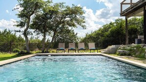 A swimming pool with lounge chairs and a deck area. - The Point-Hill Country Views-Pool+Hot Tub (Fredericksburg)