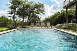 A swimming pool with lounge chairs and a deck area. - The Point-Hill Country Views-Pool+Hot Tub (Fredericksburg)