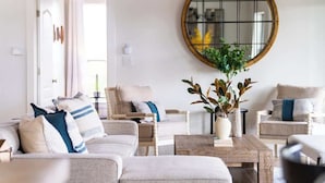A living room with a round mirror, a coffee table, and two sofas with cushions. - The Point-Hill Country Views-Pool+Hot Tub (Fredericksburg)