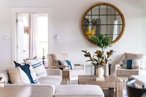 A living room with a round mirror, a coffee table, and two sofas with cushions. - The Point-Hill Country Views-Pool+Hot Tub (Fredericksburg)