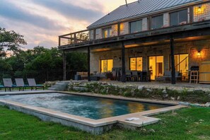A modern house with a pool, outdoor seating, and a covered patio area. - The Point-Hill Country Views-Pool+Hot Tub (Fredericksburg)