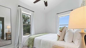 A bedroom with a bed, a nightstand, a lamp, and a window with curtains. - The Point-Hill Country Views-Pool+Hot Tub (Fredericksburg)
