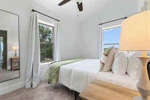 A bedroom with a bed, a nightstand, a lamp, and a window with curtains.
