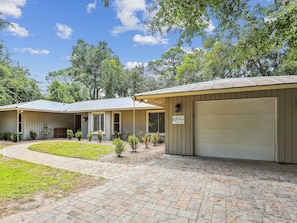 A single-story building with a garage, a covered porch, and a paved driveway.