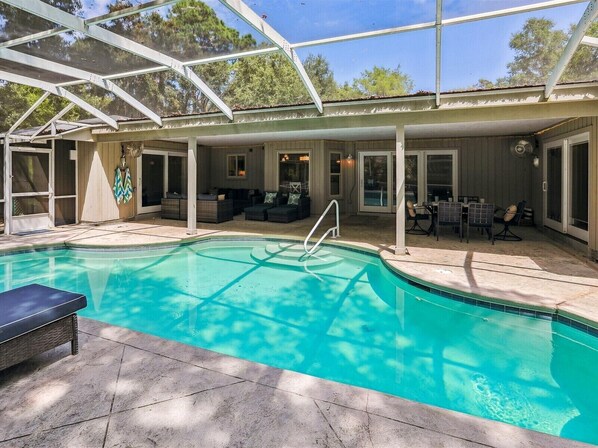 A covered swimming pool with a glass ceiling, outdoor seating, and a patio area.