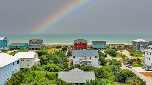 Zona residencial costera con casas, una playa y un arcoíris.