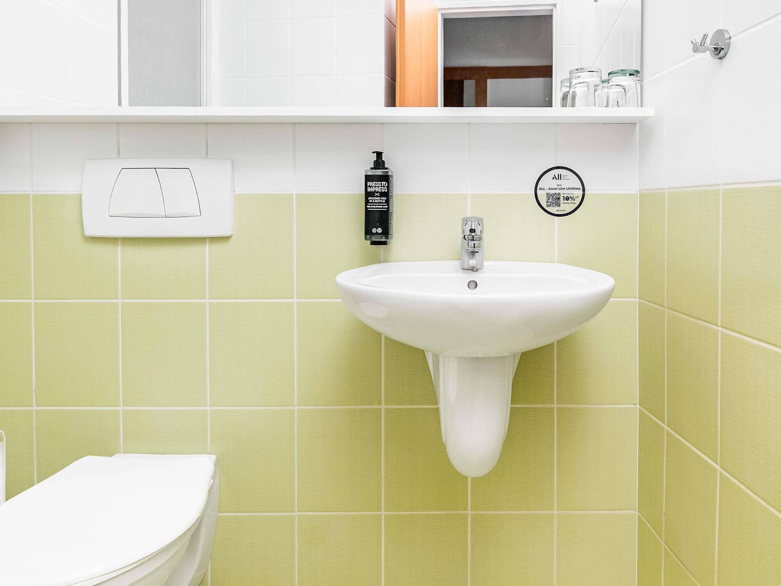 A bathroom with a white sink, a hand soap dispenser, and a towel rack.