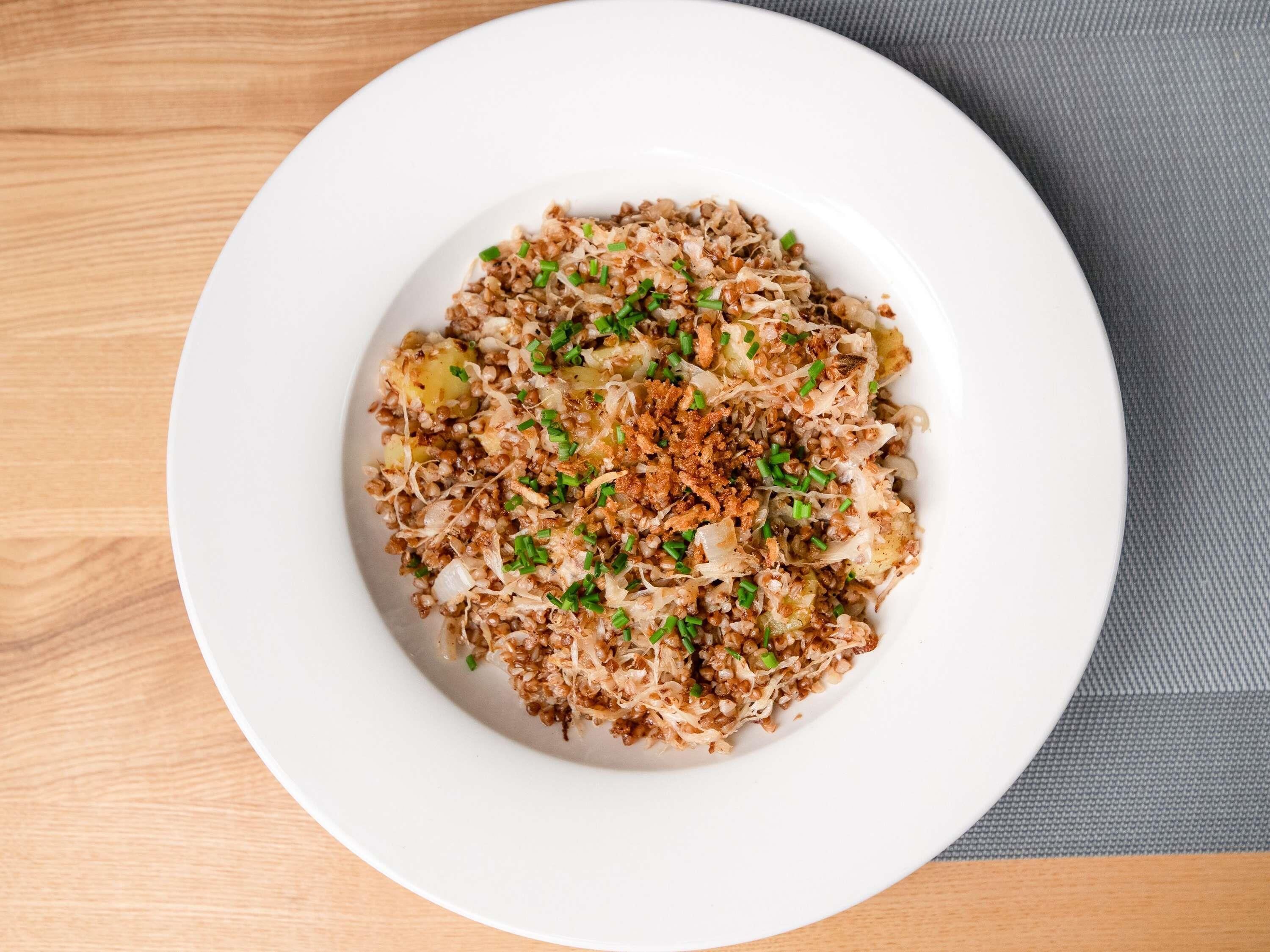 A white plate with a dish of food on a wooden table.