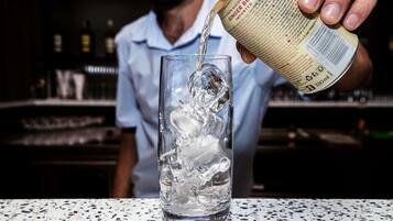 A person pouring a beverage into a glass with ice cubes.