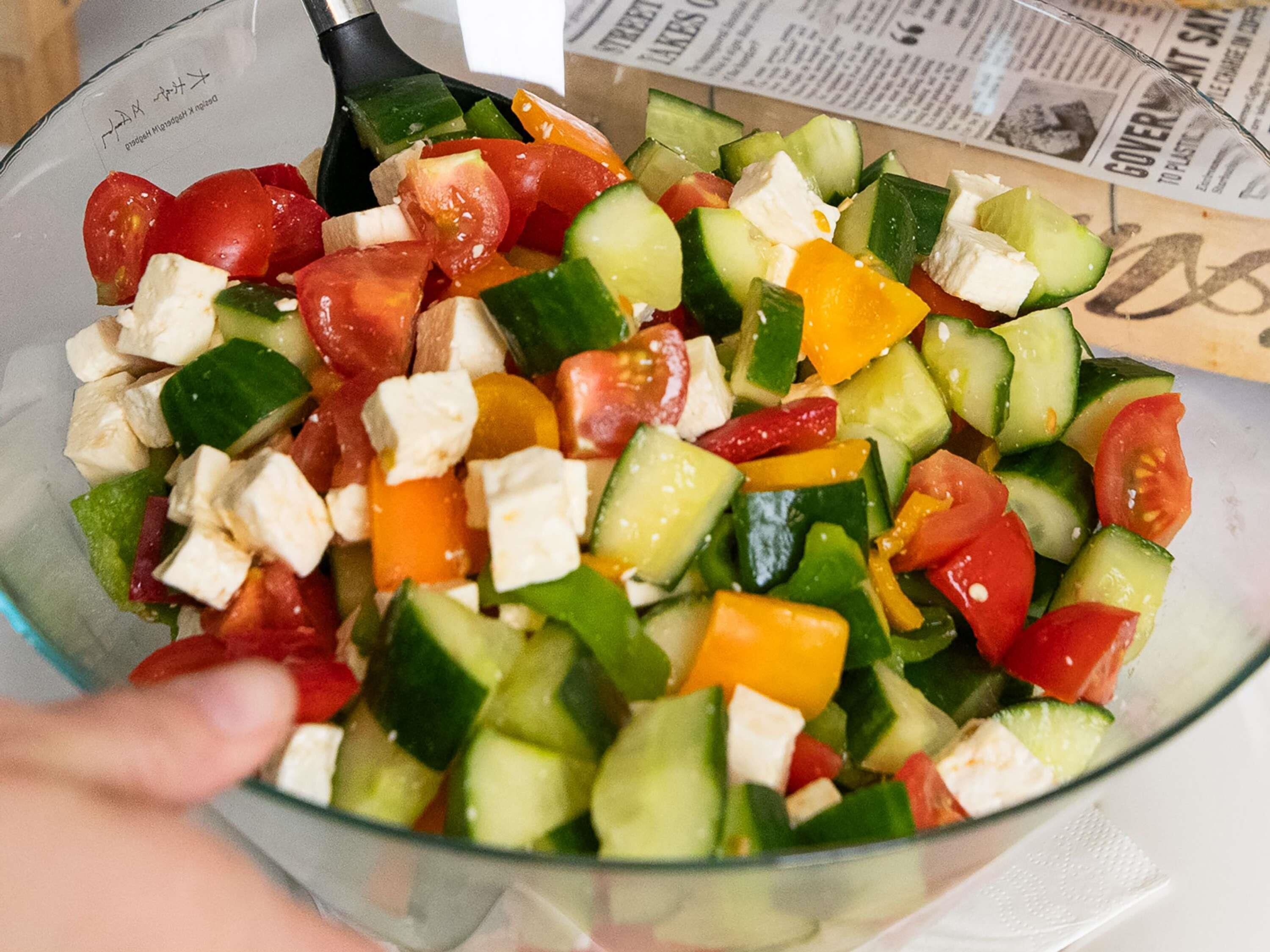 A bowl of mixed vegetables including cucumbers, tomatoes, and cheese.