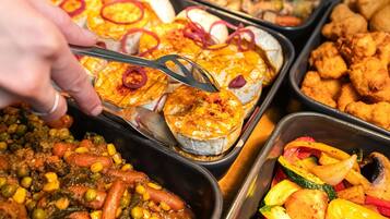 A buffet with various dishes including baked items, fried foods, and a vegetable stir.