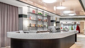 A modern bar area with a granite countertop, a coffee machine, and shelves stocked with various bottles. - ibis Styles Relax Roznov pod Radhostem (Roznov Pod Radhostem)