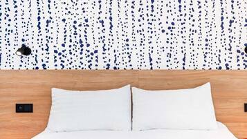 A bed with white bedding, a wooden headboard, and a speckled wall.