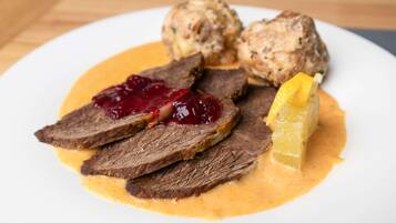 Ein Teller mit geschnittenem Fleisch, einer Kugel Soße und einem Stück Obst.