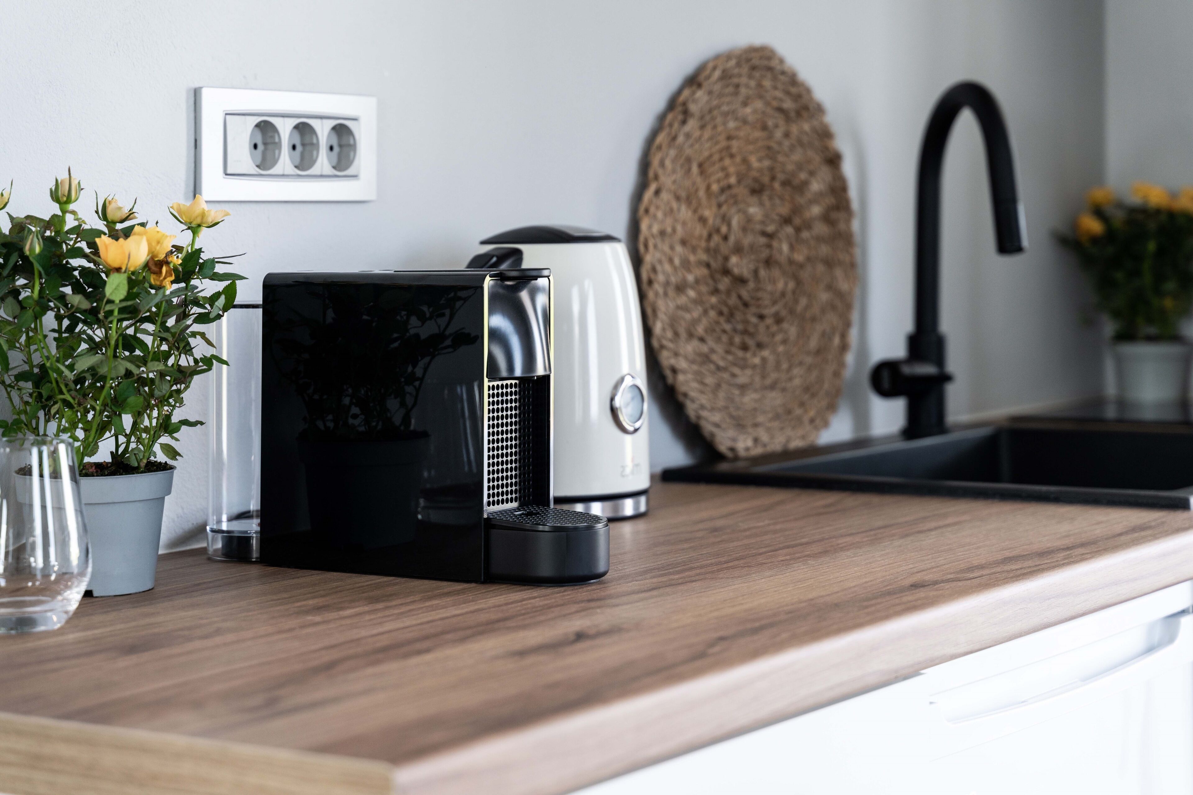 Eine Küchenarbeitsplatte mit Kaffeemaschine, einer Topfpflanze und einem gewebten Korb.