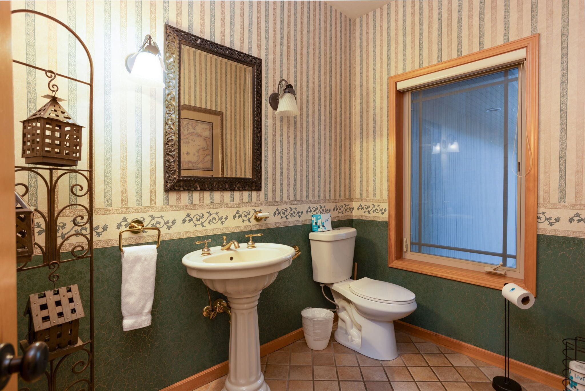 A bathroom with a pedestal sink, toilet, and a window.