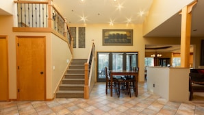 A spacious living area with a staircase, a dining table, and a kitchen area. - Cypress 4 - Huge Home, Foosball, BBQ, Dog Friendly (Sunriver)