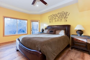 A bedroom with a large bed, a nightstand, a lamp, and a wall art piece.