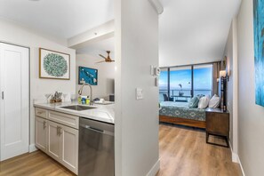 A modern kitchen with a dishwasher, a dining area with a view, and a bedroom with a balcony.